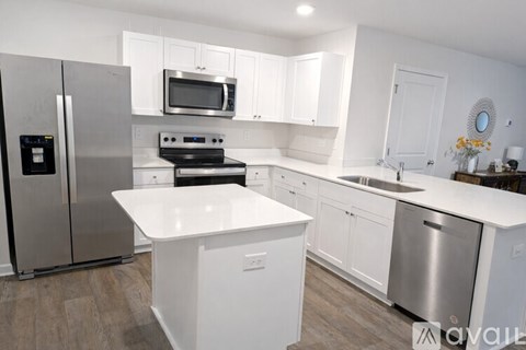 A kitchen with white cabinets and a stainless steel refrigerator.