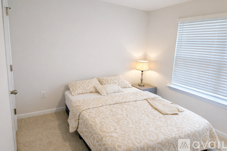 A bedroom with a bed, lamp, and carpet.