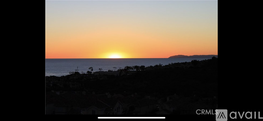 A sunset over the ocean with a mountain in the distance.