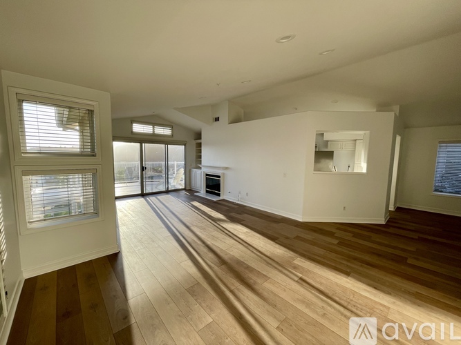 A spacious room with wooden flooring and a large window.