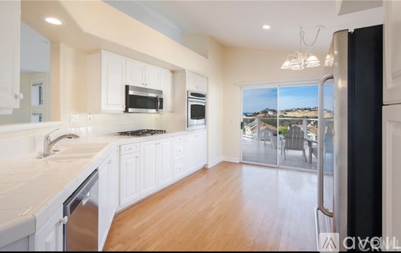 A kitchen with white cabinets and a black refrigerator.