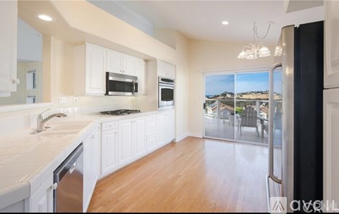 A kitchen with white cabinets and a black refrigerator.