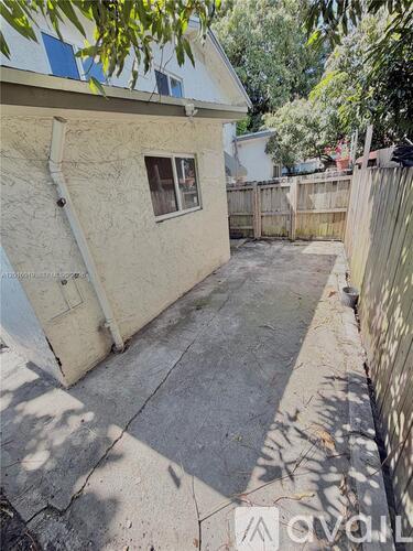 A backyard with a concrete slab and a wooden fence.