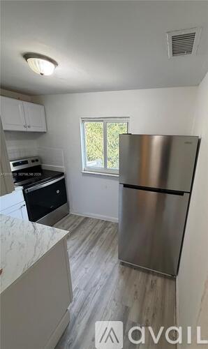 A kitchen with a refrigerator, stove, and cabinets.