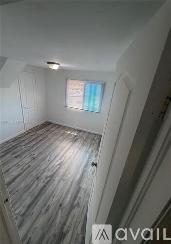 A room with wooden flooring and a window.