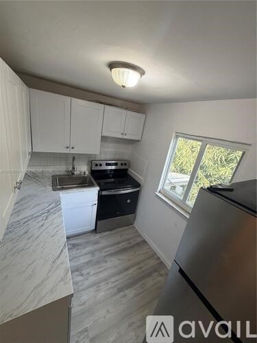 A kitchen with white cabinets and a marble countertop.