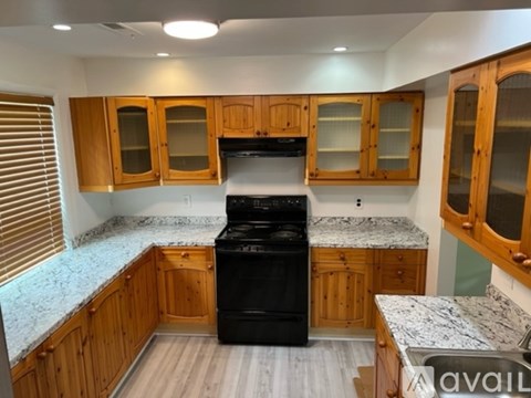 A kitchen with wooden cabinets and a black dishwasher.