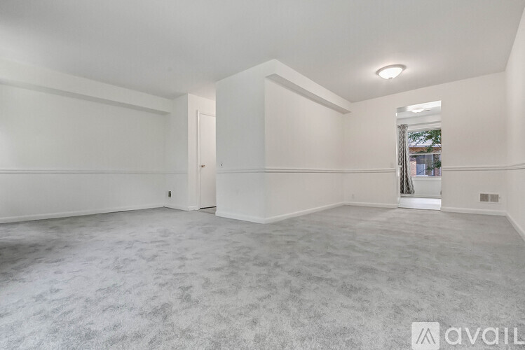 A spacious empty room with a carpeted floor and white walls.