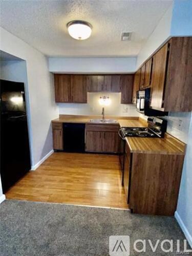 A kitchen with wooden cabinets and a black refrigerator.