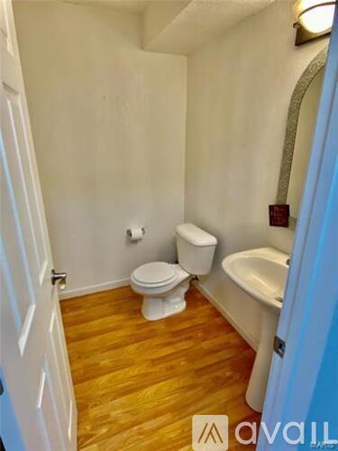 A bathroom with a toilet, sink, and mirror.