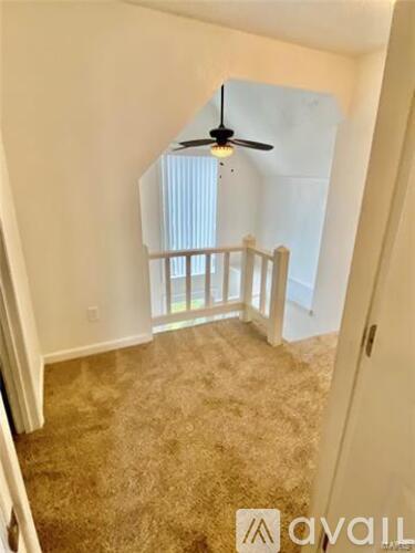 A room with a ceiling fan and carpeted floor.