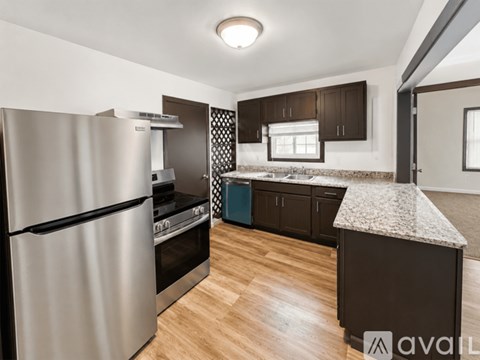 A kitchen with a stainless steel refrigerator and wooden flooring.