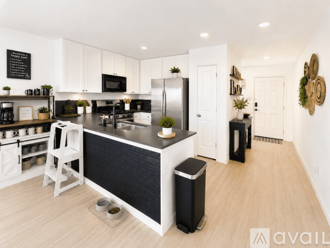 A modern kitchen with white cabinets and black countertops.