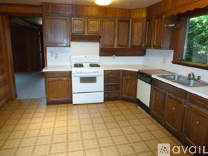 A kitchen with wooden cabinets and a white stove top oven.