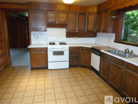A kitchen with wooden cabinets and a white stove top oven.
