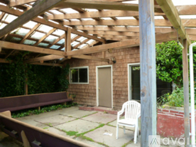 A patio with a white chair and a wooden pergola.