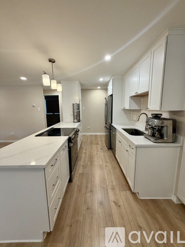 A modern kitchen with white cabinets and wooden flooring.