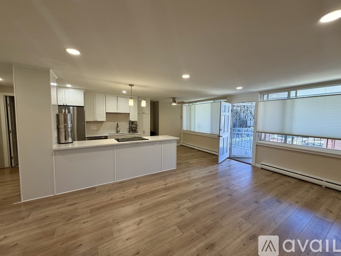 A spacious kitchen with white cabinets and a wooden floor.