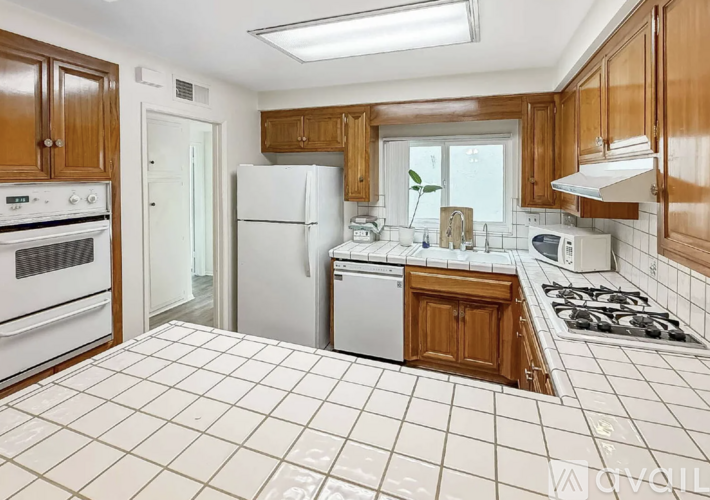 A kitchen with white appliances and wooden cabinets.