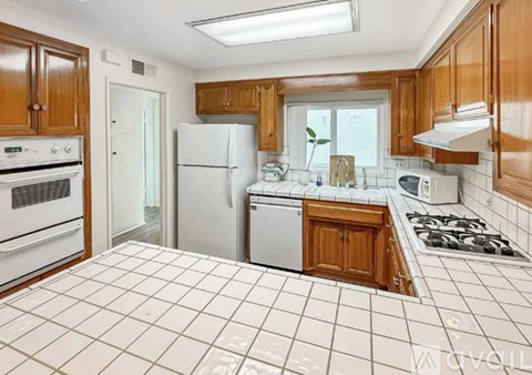 A kitchen with white appliances and wooden cabinets.