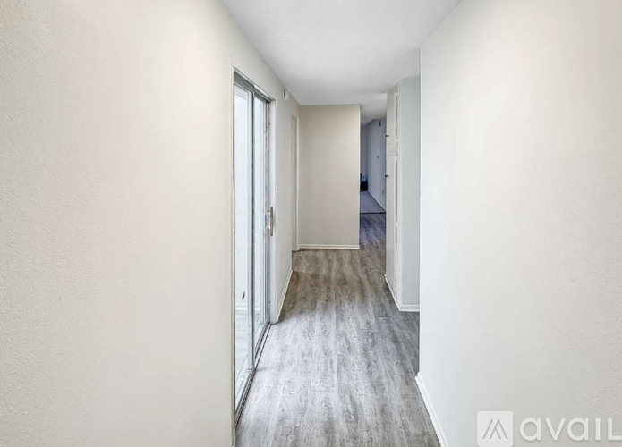 A long hallway with a door on the left and a bedroom at the end.