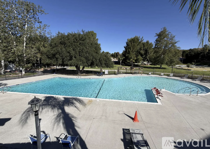 A large outdoor swimming pool surrounded by trees and lounge chairs.