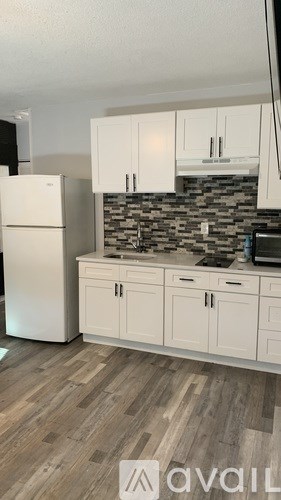 A kitchen with white cabinets and a stone backsplash.