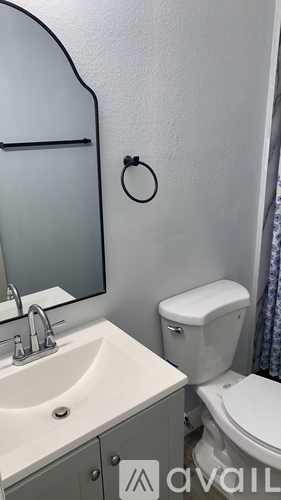 A bathroom with a toilet, sink, and mirror.