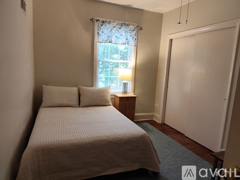 A bedroom with a bed, nightstand, and window.