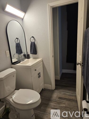 A bathroom with a toilet, sink, and mirror.