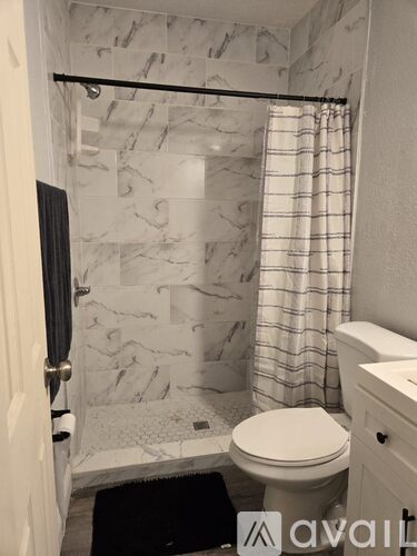 A bathroom with a marble tile shower and a white toilet.