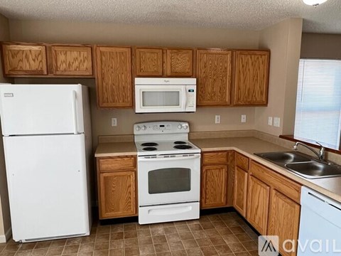 A kitchen with white appliances and wooden cabinets.