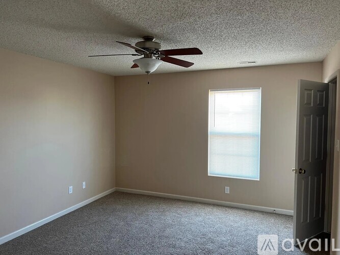 A room with a ceiling fan and a window with blinds.