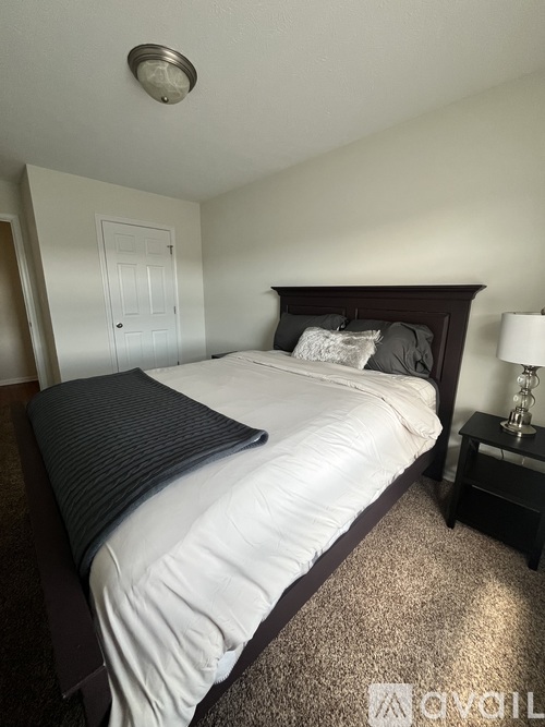 A bedroom with a bed, nightstand, and lamp.