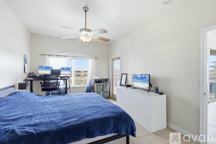 A bedroom with a bed, desk, and ceiling fan.
