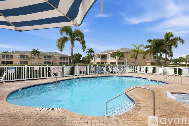A pool surrounded by chairs and palm trees.