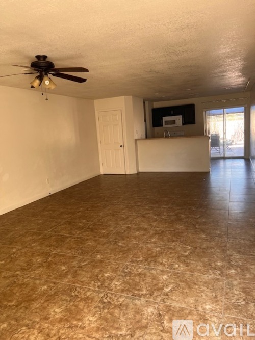 A room with a ceiling fan and a counter with a microwave.