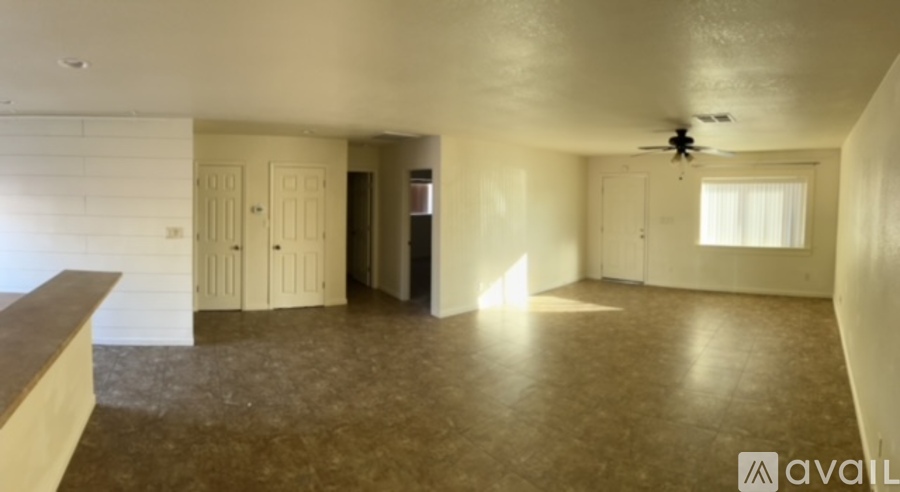 A room with a ceiling fan and a window with sunlight coming through.