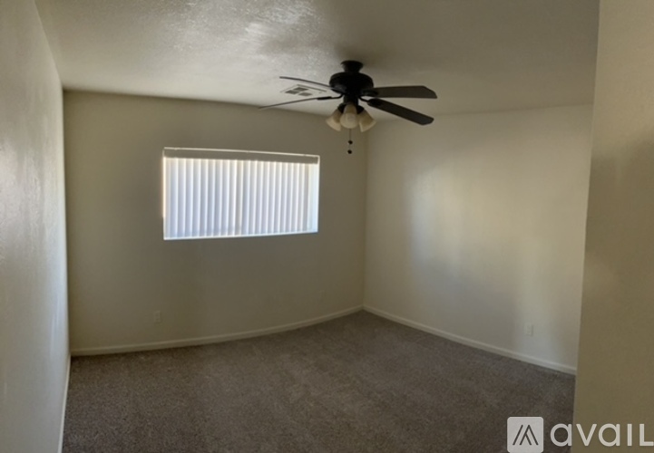 A room with a ceiling fan and a window with blinds.