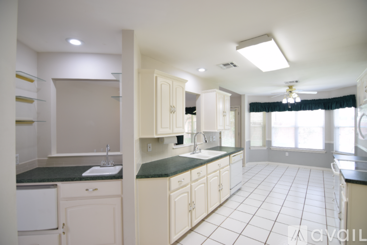 A kitchen with white cabinets and a black countertop.