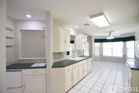 A kitchen with white cabinets and a black countertop.