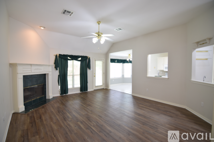A spacious living room with wood flooring and a fireplace.