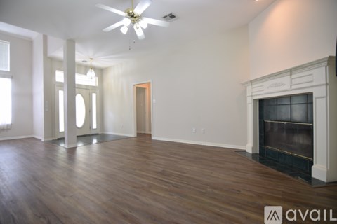 A spacious room with a fireplace and wooden floors.