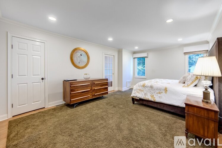 A bedroom with a bed, dresser, and a window with a view of the sky.