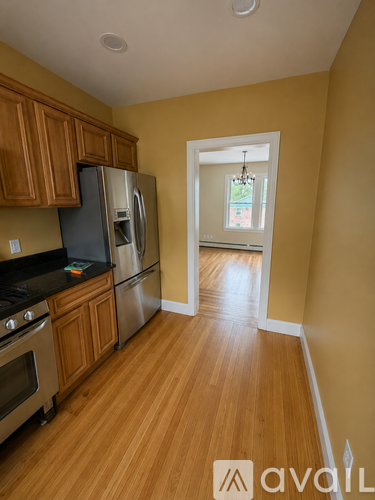 A kitchen with wooden cabinets and a stainless steel refrigerator.