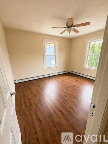 A room with a ceiling fan and wooden flooring.