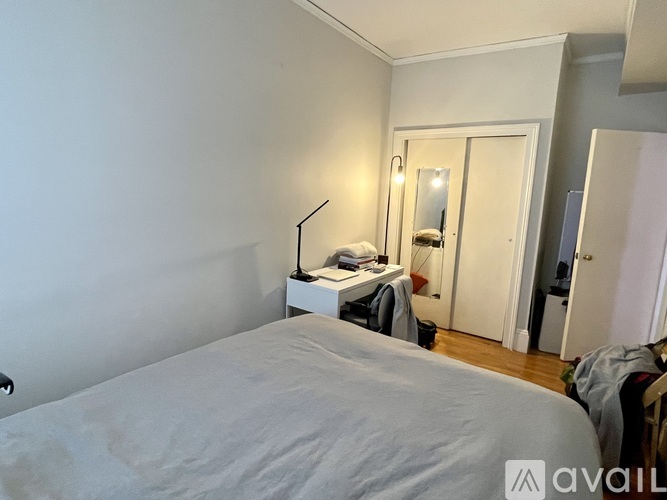 A bedroom with a bed, a nightstand with a lamp, and a mirror.