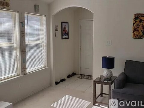 A living room with a couch, a table with a lamp, and a picture on the wall.