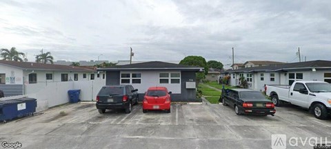 A parking lot with several cars and a building in the background.