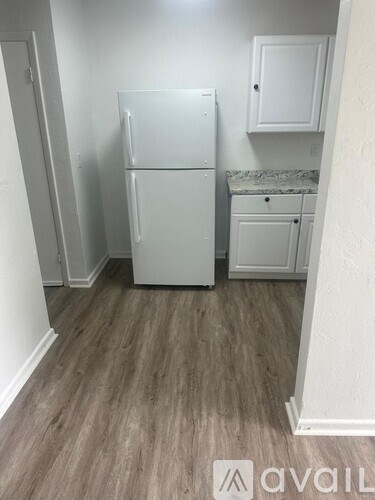 A small kitchen with a white refrigerator and cabinets.